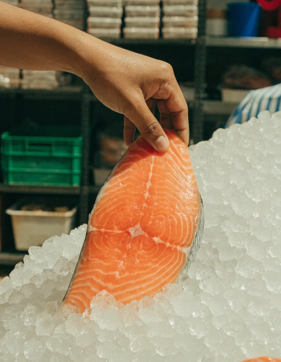 A fresh salmon fillet on crushed ice in a bright market display